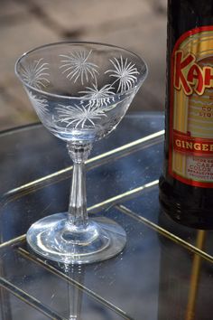 an empty wine glass sitting on top of a table next to a bottle of beer