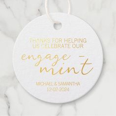 a white ornament with gold foil on it that says, thanks for helping us celebrate our engagement