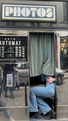 a woman is sitting in an atm machine on the side of the street with her head down