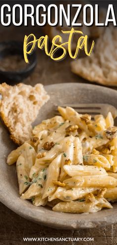 this is an image of a pasta dish on a plate with bread in the background