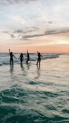 four people standing in the ocean holding hands