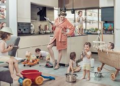 a woman in a bathrobe standing next to children sitting on the kitchen floor