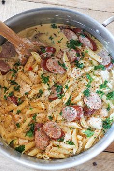 pasta with sausage, tomatoes and parsley in a pan on a wooden table top