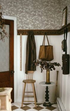 a wooden chair sitting next to a table with a bag on it's back