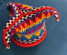 a multicolored knitted hat sitting on top of a blue surface