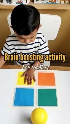 a little boy sitting at a table with a ball and sticker on it that says brain boostering activity for toddlers