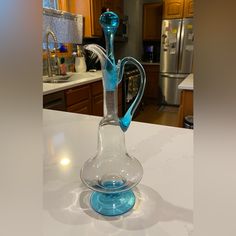 a blue glass vase sitting on top of a counter in a kitchen next to a refrigerator