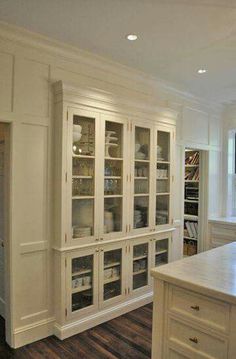 a kitchen with white cabinets and wooden floors