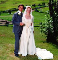 a bride and groom pose for a photo in front of a fence on their wedding day