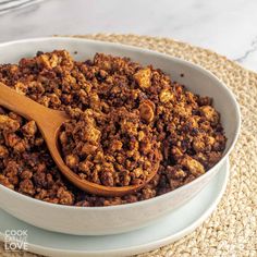 a wooden spoon in a white bowl filled with granola