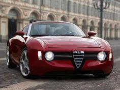 a red sports car parked in front of a building on a brick road next to a street