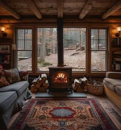 a living room filled with furniture and a fire place next to a large window covered in logs