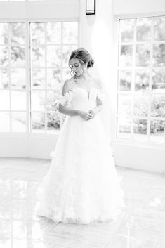 a woman in a wedding dress standing next to a window