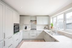 a kitchen with white cabinets and marble counter tops