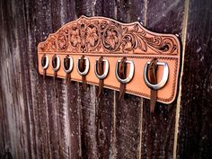 a leather coat rack with five hooks on the side of a wooden door, hanging from it's sides