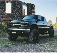 a black truck parked in front of a stone building