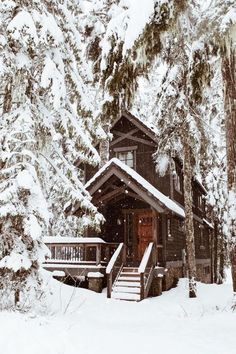 a cabin in the woods with snow on the ground and stairs leading up to it