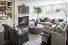 a living room filled with furniture and a fire place under a window next to a fireplace