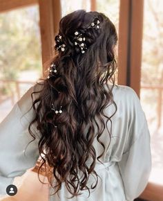 the back of a woman's head with long hair and flowers in her hair