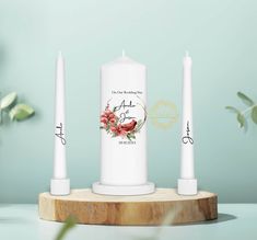 two white candles sitting on top of a wooden stand