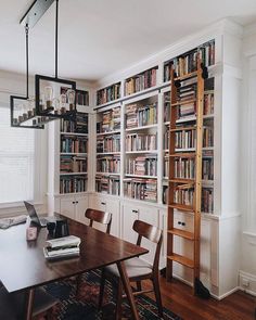 a dining room table with chairs and bookshelves