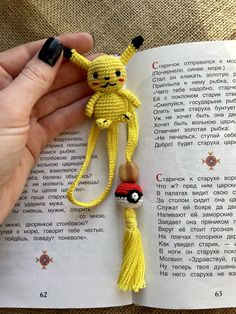 a person is holding a bookmark made out of yarn