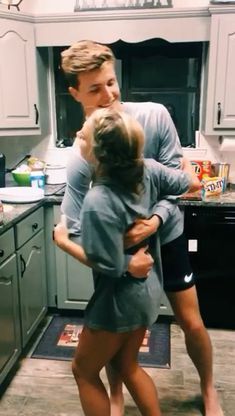 a man and woman hug in the kitchen