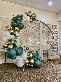 an arch made out of balloons and greenery in the middle of a carpeted room