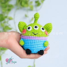 a small crocheted green and blue toy in the palm of someone's hand