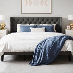 a bed with blue and white sheets in a bedroom next to two lamps on either side of the bed