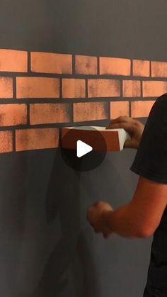 a man is painting a brick wall with orange paint