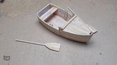 a small wooden boat sitting on top of a cement floor next to an oar