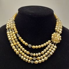 Step back in time with this beautiful 1950s vintage necklace. Features a cluster of pale yellow faux pearl beads that connects to multiple strands of clear glass beads, pale yellow faux pearl beads in different shapes and beautiful gold tone findings, complimenting each other very well. Easy to wear with a gold tone hook clasp. Treat yourself to this vintage gem or gift a loved one who adores vintage accessories, this necklace is sure to become a favorite in any vintage jewelry collection. Signed JAPAN. Circa 1950s/1960s. TO VIEW MORE FROM NEW VINTAGE FOR YOU, GO HERE: https://newvintageforyou.etsy.com All vintage items are sold as is in pictured condition. I do not alter or repair any vintage items because I feel it is important to maintain the authentic history of the piece. The photos a Twist Beads, Multi Strand Beaded Necklace, Vintage Beads Necklace, Vintage Necklaces, Hook Clasp, Multi Strand Necklace, Jewelry Companies, 1950s Vintage, Pale Yellow