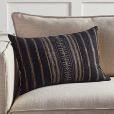 a black and gold striped pillow sitting on top of a beige couch next to a white wall