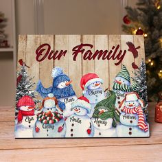 a wooden sign with snowmen on it that says our family and is decorated with christmas decorations