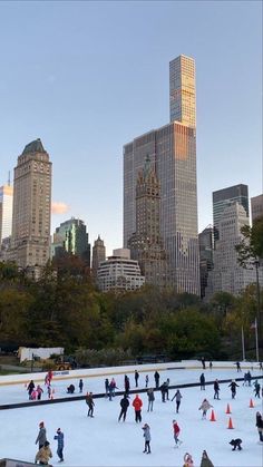 people skating on an ice rink in front of the city skyline with skyscrapers and tall buildings