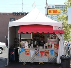 a tent with food and drinks on the side in front of a building that says tatoo