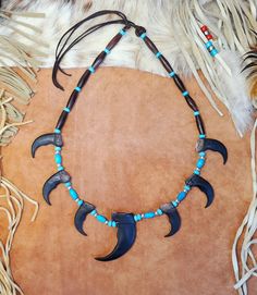 Grizzly Bear Claw Necklace handmade with imitation bear claws made from resin.  Necklace includes hairpipe beads, turquoise and silver plated beads with an adjustable deerskin tie in back.  Include six 2" faux bear claws and one 3" faux bear claw.  Great for SASS shooting, costumes, Native American Indian PowWows and more. Choose Brown Rosewood,  BrownAmber Horn, Black Horn or Buffalo Bone Hairpipe Beads.  If you would like a custom one of these made differently, just message me. See my other listings for Hat Bands, Horse Hair Keepsakes, Boot Bracelets, Earrings, Chokers, Hair Feather Clips, Bolo Ties, Dreamcatchers, Glasses and Mask Holders, Necklaces and more. Tami Blue Eyes Designs www.BlueEyesDesignsHB.com BlueEyesDesignsHB@gmail.com Tulsa King, Hunting Crafts, Bear Claw Necklace, Hair Keepsake, Necklace Drawing, Boot Bracelet, Claw Necklace, Antler Necklace, Bear Claw