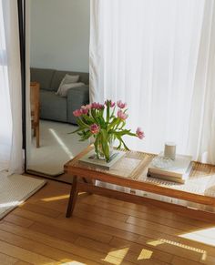 a coffee table with flowers on it in front of a window