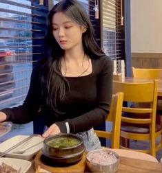 a woman sitting at a table in front of a plate of food with chopsticks