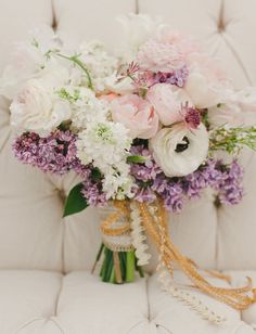 a bouquet of flowers sitting on top of a white couch next to a pillow and chair