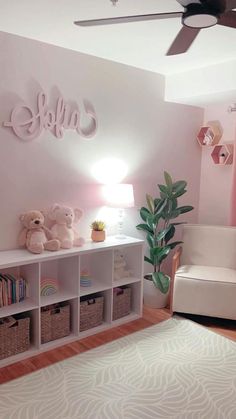 a pink and white room with teddy bears, bookshelves and a ceiling fan