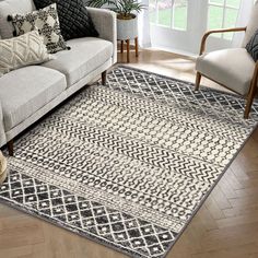 a living room area with a couch, chair and rug on the floor in front of a window