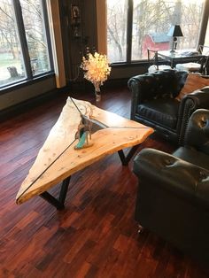 a living room filled with furniture and a wooden table in front of large windows on top of hard wood flooring