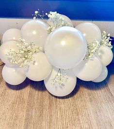 white balloons and baby's breath flowers are arranged on a table