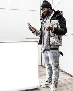 a man standing next to a white refrigerator holding a cell phone