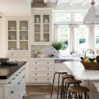 a large kitchen with white cabinets and black counter tops, along with lots of stools