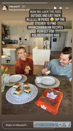 two people sitting at a table eating sandwiches