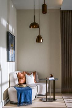 a living room with white couches and two lamps hanging from the ceiling above them