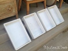 four empty white trays sitting on the ground